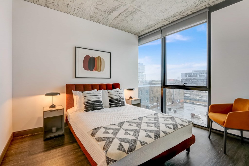 A bedroom with a large bed and a chair.