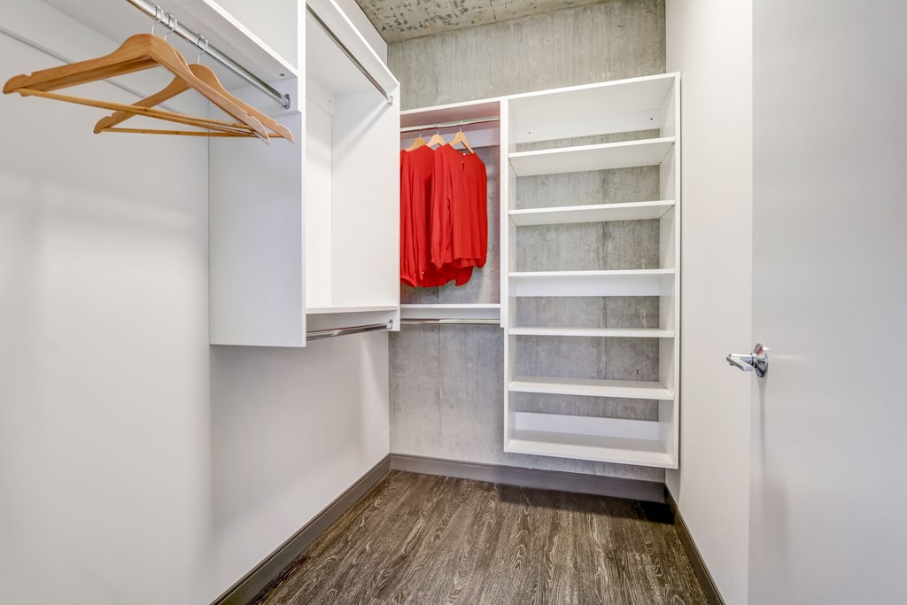 A white closet with a red sweater hanging on the shelf.