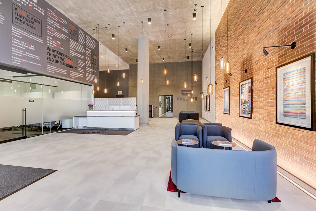 A reception area with a white counter and blue chairs.