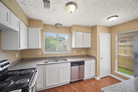 A kitchen with white cabinets and a black stove top oven.
