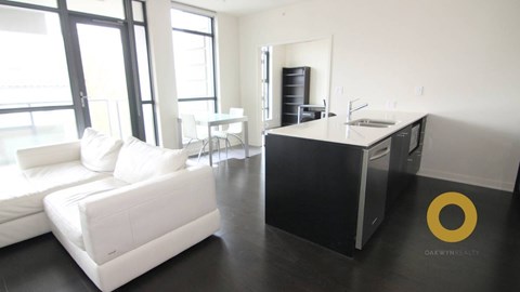 A modern living room with a white couch and a black and white kitchen.