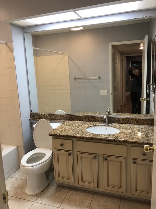 A bathroom with a toilet, sink, and mirror.