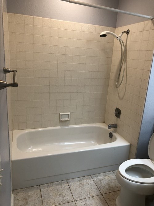 A white bathroom with a toilet, tub, and shower.