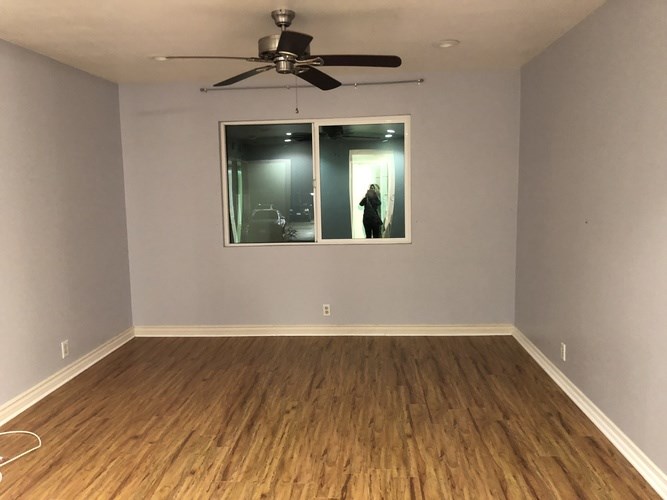 A room with a ceiling fan and wooden flooring.