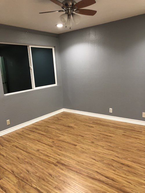 A room with a ceiling fan and wooden flooring.