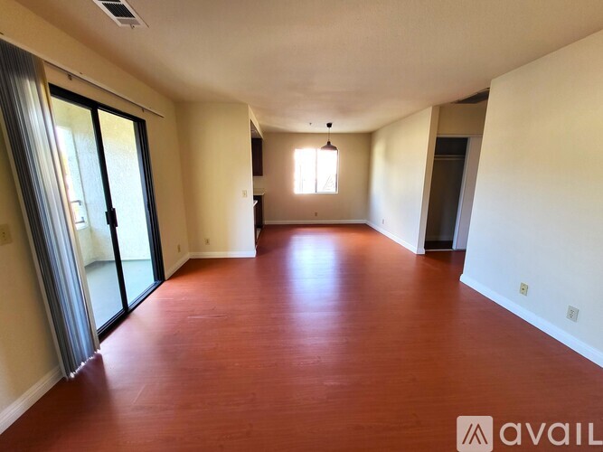 A spacious room with wooden flooring and a window.