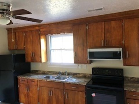 A kitchen with wooden cabinets and black appliances.