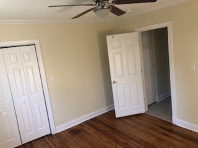 A room with a ceiling fan and two doors.