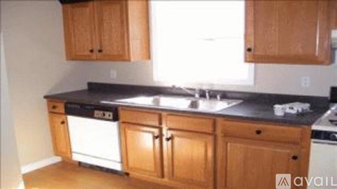 A kitchen with wooden cabinets and black countertops.