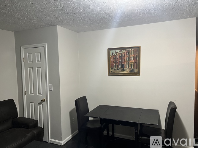A room with a table, chairs and a painting on the wall.