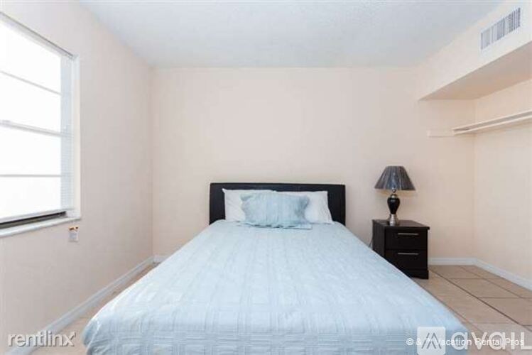 A bedroom with a bed, nightstand, and window.