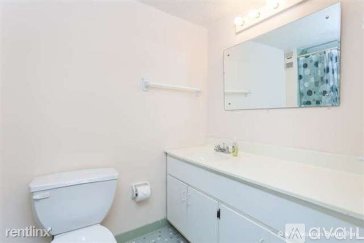 A white toilet sits next to a white sink in a small bathroom.