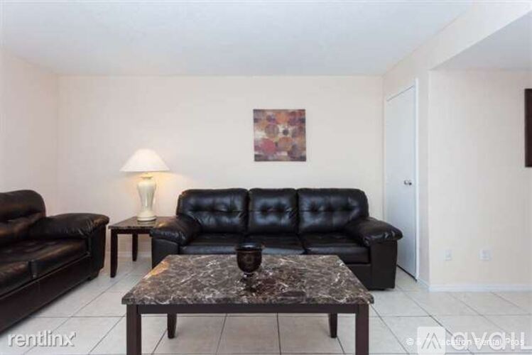 A living room with a black leather couch and a coffee table.
