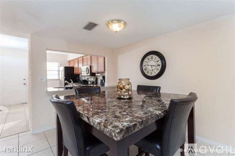 A dining room with a marble table and a clock on the wall.