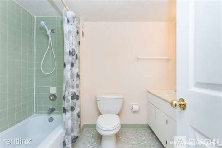 A white toilet sits in a bathroom with green tiles.