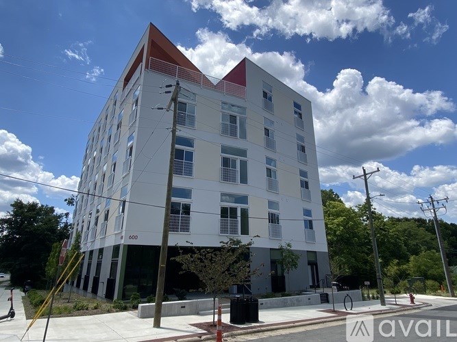 A modern white building with a red roof is under a blue sky with clouds.