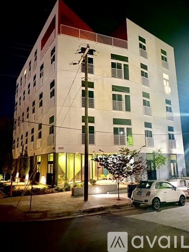 A white car is parked in front of a multi-story building at night.