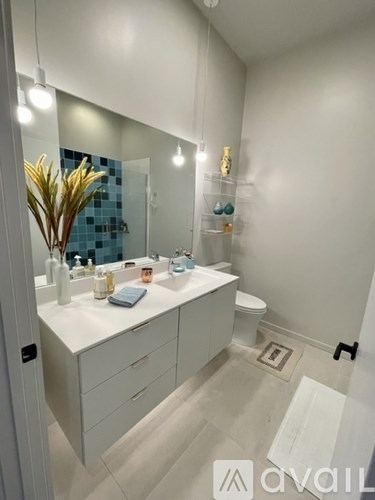 A bathroom with a white counter and a blue tiled wall.
