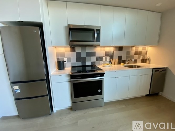 A kitchen with a refrigerator, microwave, oven, and sink.