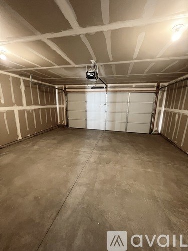 A spacious garage with a closed white door and a light on the ceiling.
