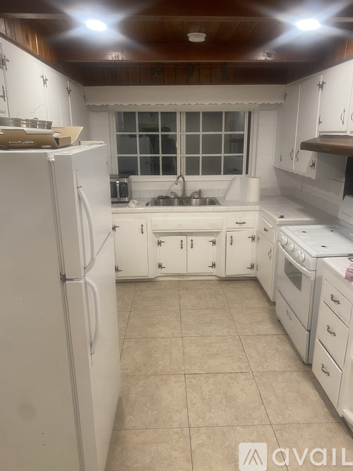 A kitchen with white appliances and cabinets.