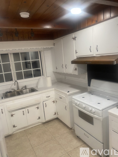 A kitchen with white cabinets and a stove top oven.
