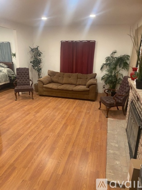 A living room with a brown couch and wooden floors.