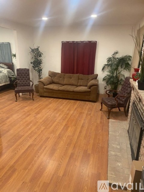 A living room with a brown couch and wooden floors.