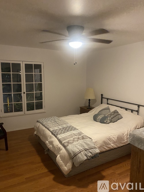 A bedroom with a bed, a ceiling fan, and a window.
