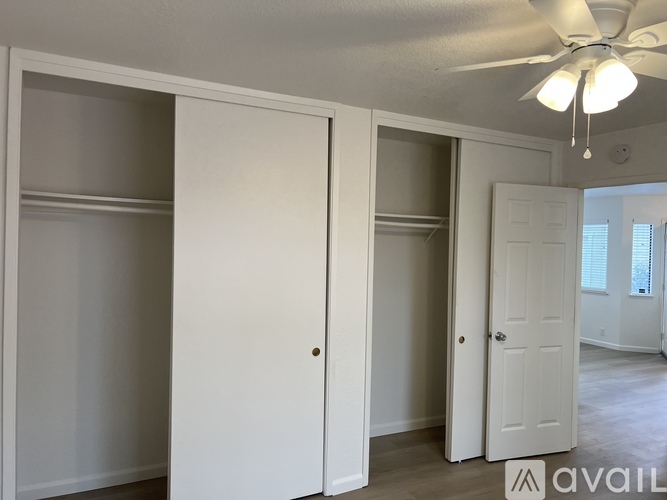A room with a ceiling fan and three doors.