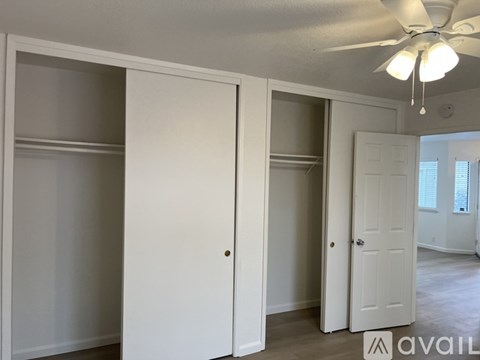 A room with a ceiling fan and three doors.