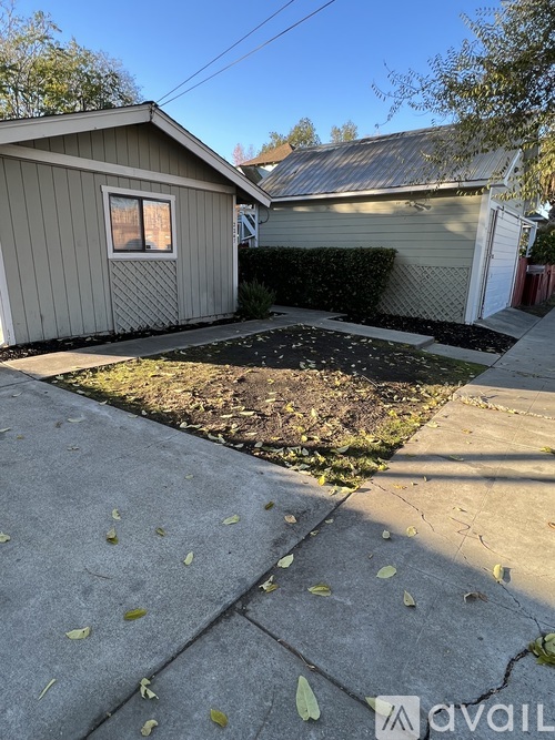 A small house with a grey roof and a small window is surrounded by a small garden.