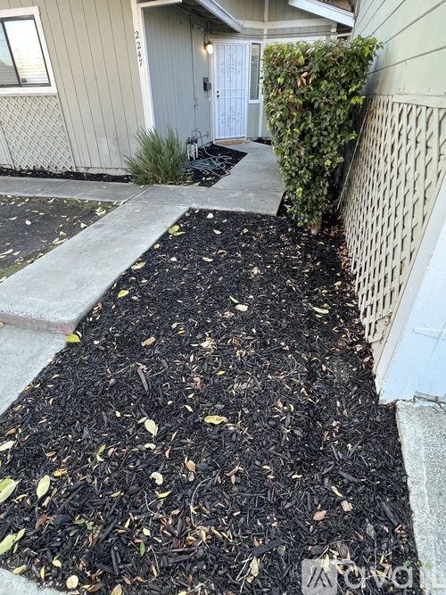 A mulched garden bed in front of a house.