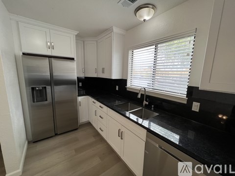 A kitchen with a black countertop and white cabinets.