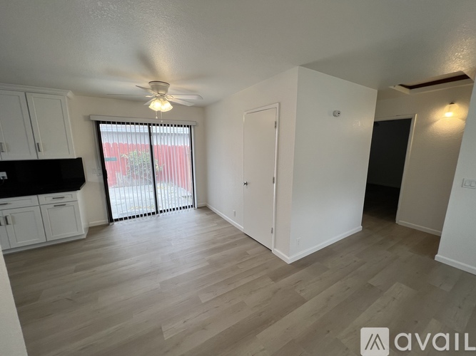 A spacious room with a ceiling fan and sliding glass doors leading to a balcony.