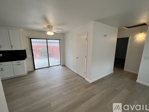 A spacious room with a ceiling fan and sliding glass doors leading to a balcony.