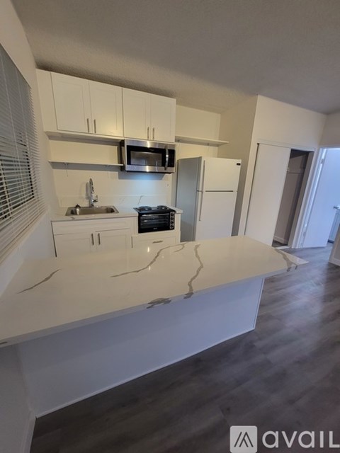 A kitchen with white cabinets and a cracked countertop.