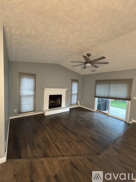 A living room with a fireplace and a ceiling fan.