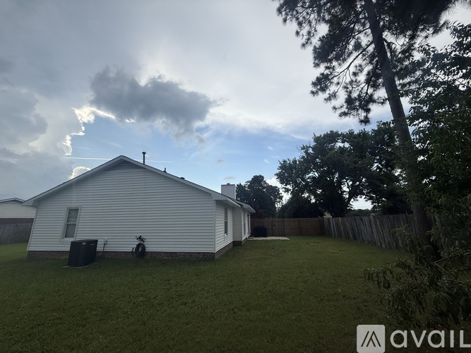 A house with a fence and trees in the background.