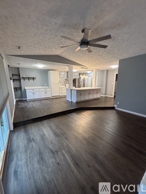 A spacious room with wood flooring and a ceiling fan.