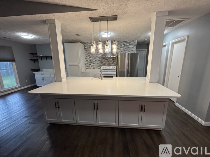 A kitchen with white cabinets and a stone backsplash.