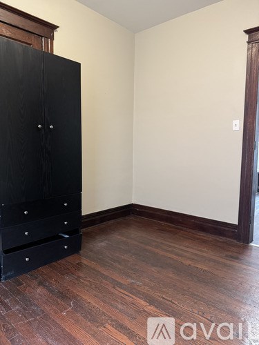 A black wardrobe with drawers is in a room with wooden floors.