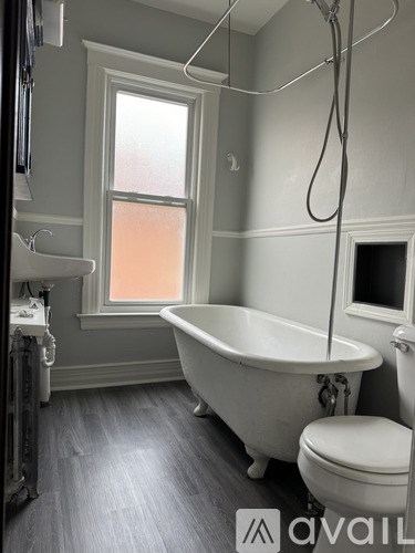 A white bathtub sits in a bathroom with a window.