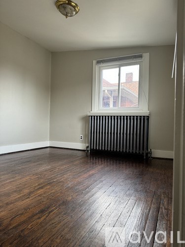 A room with a window and a radiator on the floor.