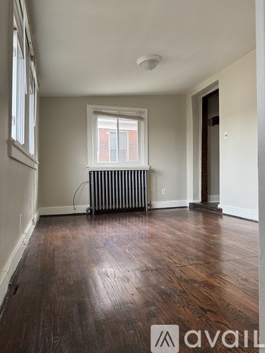 A room with wooden floors and a window with a radiator beneath it.