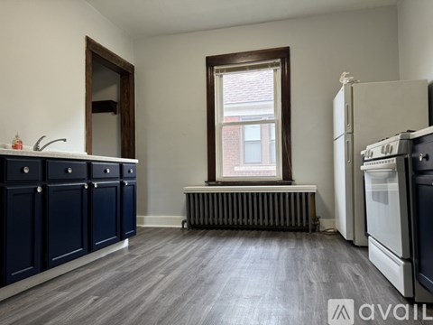 A kitchen with dark blue cabinets and a window with a view of a building outside.