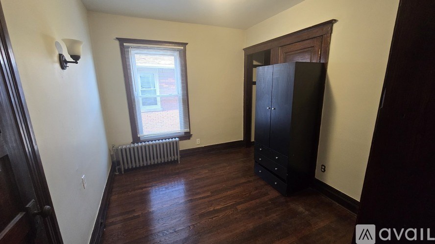 A room with a black wardrobe and a window with blinds.