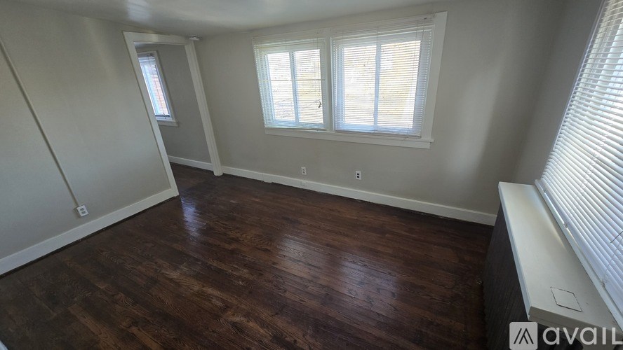 A room with wooden floors and two windows.