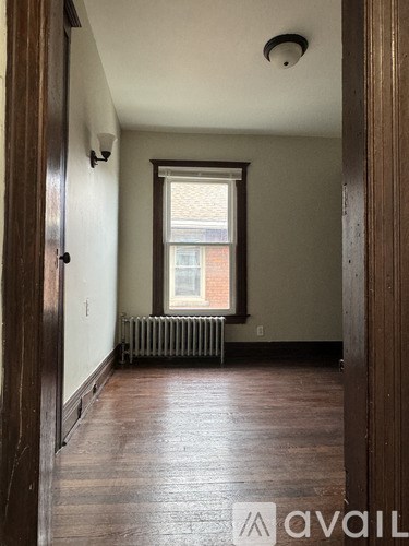 A room with wooden floors and a window with a view of a building outside.