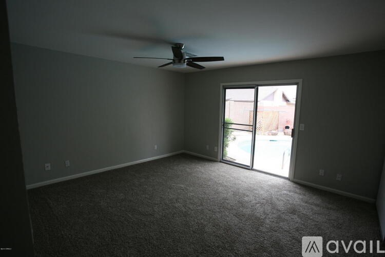 A room with a ceiling fan and a sliding glass door leading to a balcony.